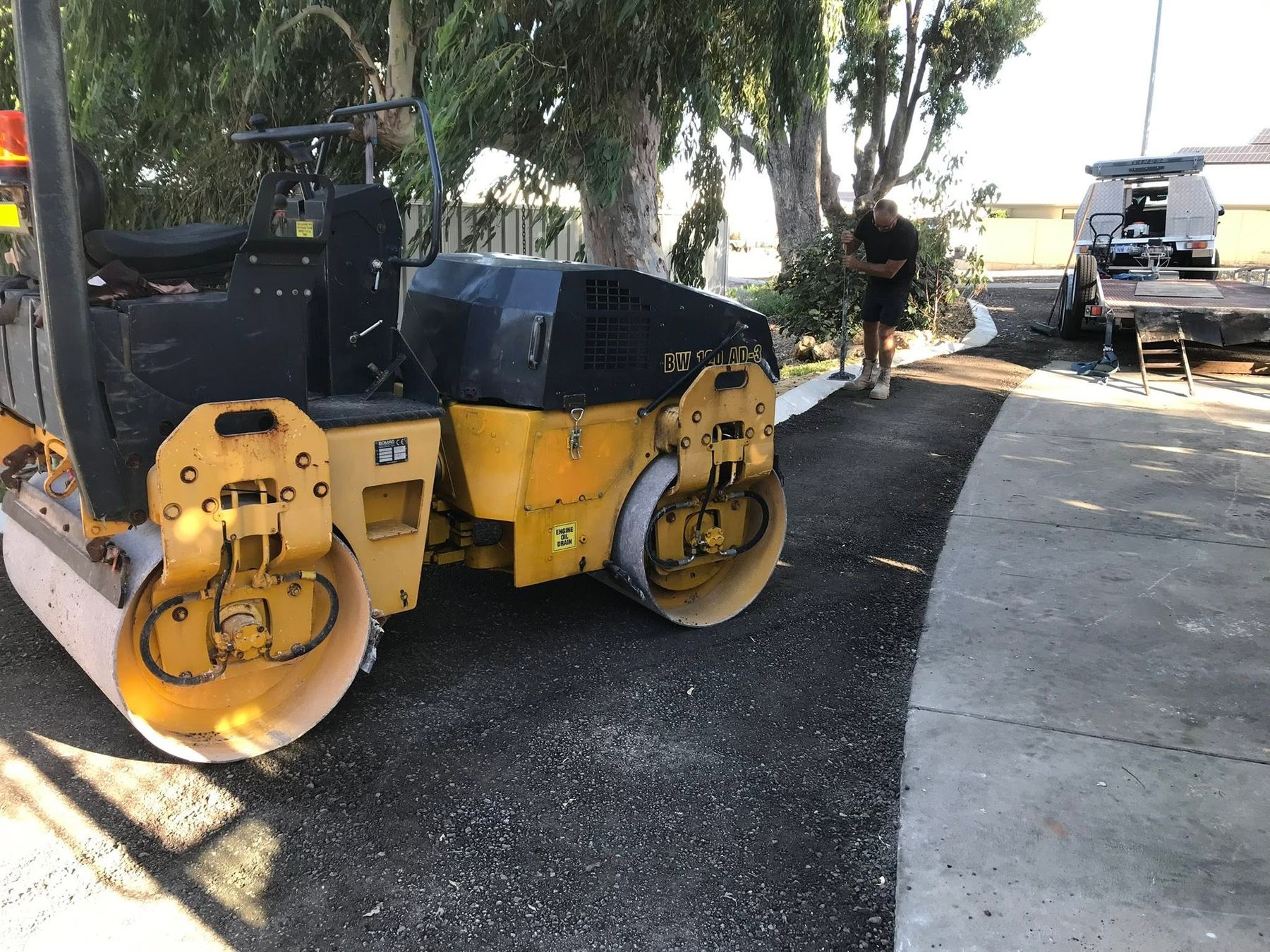 A twin-drum roller compacting a freshly laid asphalt driveway