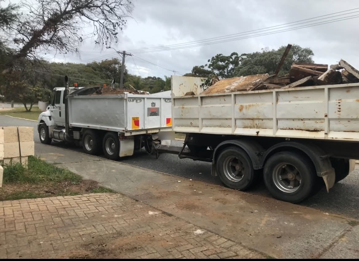 A Haste Contracting tipper with its dog trailer, both loaded with demolition waste, on a suburban street